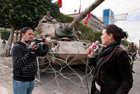 Journaliste de la télévision satellitaire privé tunisienne couvrant une manifestation de l'UGTT et interviewant les militaires sur l'avenue Habib Bourguiba à Tunis. Les journalistes tunisiens découvrent une liberté de la presse et investissent le terrain.