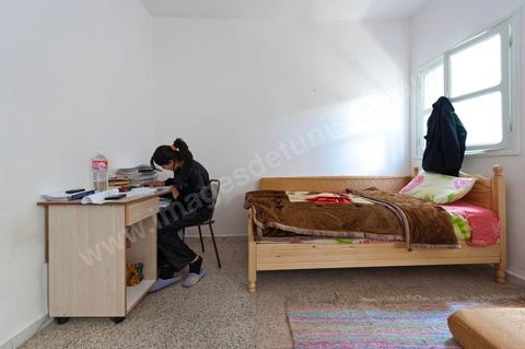 La nouvelle demeure de la famille BouaziziContrainte de quitter Sidi Bouzid, où la pression était devenue trop forte pour elle, la famille Bouazizi a trouvé refuge à 260 kilomètres de là, à Tunis. La mère de Mohamed Bouazizi, la figure emblématique du soulèvement populaire de Tunisie, ses sœurs et ses deux plus jeunes frères résident dans une maison aux carreaux de faïence bleue, trois pièces en rez-de-chaussée, dans le quartier populaire de Bousalsa à la Marsa dans la banlieue nord de Tunis. Leila, la sœur aînée, âgée de 24 ans, suit une formation professionnelle par alternance pour devenir contrôleuse qualité dans le textile ;  Semia, 19 ans, prépare son bac, Basma, 16 ans, Karim, 14 ans, et Zyed, 8 ans, poursuivent leur scolarité. Seul, le frère aîné, Salem, vit ailleurs, à Sfax. Montrée du doigt par une partie de la population de Sidi Bouzid, qui l’accuse d’avoir reçu de l’argent du gouvernement, la famille Bouazizi produit le contrat de location de sa nouvelle demeure qu’elle a prévu de louer 6 mois, jusqu’en août, au prix de 360 dinars (180 euros). Bientôt, promet la mère, elle retournera à Sidi Bouzid.