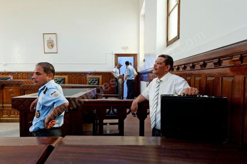 20 juin 2011 : Policiers et huissier avec la valise contenant la drogue trouvée dans le bureau de l'ancien Président. Tribunal de première Instance de Tunis, Chambre Criminelle, la justice tunisienne a entamé aujourd’hui le procès de Benali et de sa femme en son absence, cette audience est la première parmi les 93 procédures engagées contre le président déchu, dont 35 relèvent de la justice militaire.Le procès d’aujourd’hui concerne l'affaire du palais de Sidi Dherif où une importante quantité de devises et des bijoux de valeur ont été saisis. Ben Ali est également accusé de  détention d'armes et de possession de stupéfiants, saisis au palais de Carthage.  Il est passible de peines allant de 5 à 20 ans de prison. 