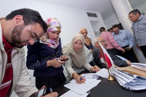 Dans le bureau Rached Ghannouchi, président et fondateur de Ennahdha, notent avec ses filles Intissar (à droite) Yosr (au centre) et Bara (à gauche) le fils notent les  résultats provisoires lors de la soirée de résultats au QG du parti Ennahda à Tunis. 
