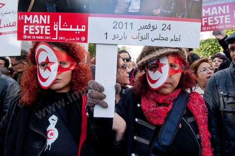14 janvier 2012 : Deux jeunes femmes promènent sur l'avenue une expo de photos de la Révolution tunisienne au nom du Manifeste du 20 mars 2011. Commémoration à Tunis du premier anniversaire de la Révolution tunisienne, le 14 janvier étant la date de la fuite de l'ex Président vers l'Arabie Saoudide. 