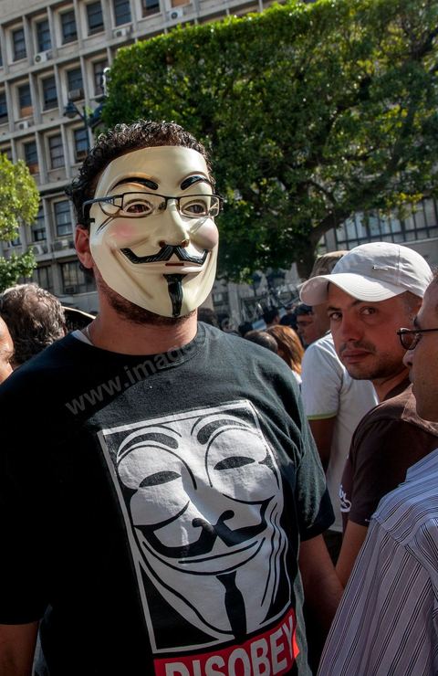 22 octobre 2012 : Un jeune activiste avec un masque de Anonymous devant le Ministère de l'Intérieur. Plus de 3000 personnes se sont rassemblées lundi sans incident à l'avenue Habib Bourguiba de Tunis pour dénoncer les violences politiques et une dérive autoritaire du pouvoir dominé par les islamistes, quelques jours après la mort d'un opposant politique. A l'apel de la troika de l'oppostion Nidaa Tounes, Al Jomhouri et Al Massar, les slogans criés dénoncent l’extrémisme et la violence politique, synonymes de terrorisme et de dictature et appellent à la dissolution des comités de protection de la Révolution, responsables, selon eux, de l’assassinat de Lotfi Nagdh, coordinateur de Nida Tounes à Tataouine, le 18 octobre. D’ailleurs, un portrait du disparu est brandi par les manifestants.