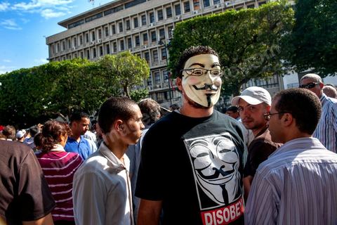 22 octobre 2012 : Un jeune activiste avec un masque de Anonymous devant le Ministère de l'Intérieur. Plus de 3000 personnes se sont rassemblées lundi sans incident à l'avenue Habib Bourguiba de Tunis pour dénoncer les violences politiques et une dérive autoritaire du pouvoir dominé par les islamistes, quelques jours après la mort d'un opposant politique. A l'apel de la troika de l'oppostion Nidaa Tounes, Al Jomhouri et Al Massar, les slogans criés dénoncent l’extrémisme et la violence politique, synonymes de terrorisme et de dictature et appellent à la dissolution des comités de protection de la Révolution, responsables, selon eux, de l’assassinat de Lotfi Nagdh, coordinateur de Nida Tounes à Tataouine, le 18 octobre. D’ailleurs, un portrait du disparu est brandi par les manifestants.