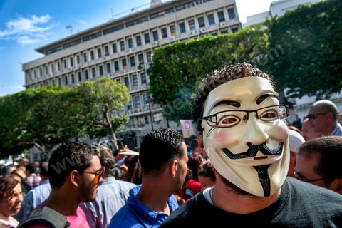 22 octobre 2012 : Un jeune activiste avec un masque de Anonymous devant le Ministère de l'Intérieur. Plus de 3000 personnes se sont rassemblées lundi sans incident à l'avenue Habib Bourguiba de Tunis pour dénoncer les violences politiques et une dérive autoritaire du pouvoir dominé par les islamistes, quelques jours après la mort d'un opposant politique. A l'apel de la troika de l'oppostion Nidaa Tounes, Al Jomhouri et Al Massar, les slogans criés dénoncent l’extrémisme et la violence politique, synonymes de terrorisme et de dictature et appellent à la dissolution des comités de protection de la Révolution, responsables, selon eux, de l’assassinat de Lotfi Nagdh, coordinateur de Nida Tounes à Tataouine, le 18 octobre. D’ailleurs, un portrait du disparu est brandi par les manifestants.