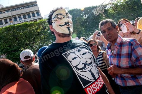 22 octobre 2012 : Un jeune activiste avec un masque de Anonymous devant le Ministère de l'Intérieur. Plus de 3000 personnes se sont rassemblées lundi sans incident à l'avenue Habib Bourguiba de Tunis pour dénoncer les violences politiques et une dérive autoritaire du pouvoir dominé par les islamistes, quelques jours après la mort d'un opposant politique. A l'apel de la troika de l'oppostion Nidaa Tounes, Al Jomhouri et Al Massar, les slogans criés dénoncent l’extrémisme et la violence politique, synonymes de terrorisme et de dictature et appellent à la dissolution des comités de protection de la Révolution, responsables, selon eux, de l’assassinat de Lotfi Nagdh, coordinateur de Nida Tounes à Tataouine, le 18 octobre. D’ailleurs, un portrait du disparu est brandi par les manifestants.