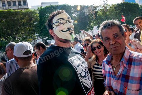 22 octobre 2012 : Un jeune activiste avec un masque de Anonymous devant le Ministère de l'Intérieur. Plus de 3000 personnes se sont rassemblées lundi sans incident à l'avenue Habib Bourguiba de Tunis pour dénoncer les violences politiques et une dérive autoritaire du pouvoir dominé par les islamistes, quelques jours après la mort d'un opposant politique. A l'apel de la troika de l'oppostion Nidaa Tounes, Al Jomhouri et Al Massar, les slogans criés dénoncent l’extrémisme et la violence politique, synonymes de terrorisme et de dictature et appellent à la dissolution des comités de protection de la Révolution, responsables, selon eux, de l’assassinat de Lotfi Nagdh, coordinateur de Nida Tounes à Tataouine, le 18 octobre. D’ailleurs, un portrait du disparu est brandi par les manifestants.