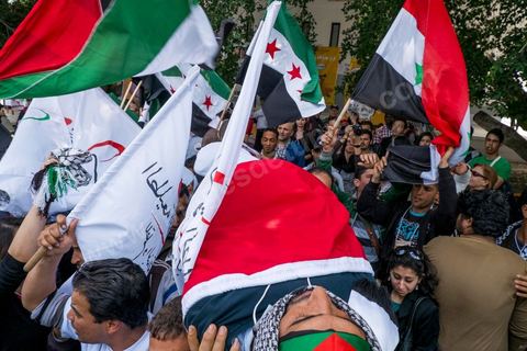 29 mars 2013 : face à face très tendu et légers affrontements entre des syriens pro rebellion (drapeau trois étoiles rouges) et militants tunisiens du parti Bass pro Bachar El Assad avec au milieu des manifestants pro palestiniens brandissant un faux cadavre sur la place centrale du FSM au dernier jour des rencontres du Forum Social Mondial sur le campus universitaire de Tunis. Ce premier forum en Terre arabe a été fortement marqué par les revendicatiosn et constatestations nationaliste arabes, et dominé par un hommage et soutien constant au peuple palestinien.