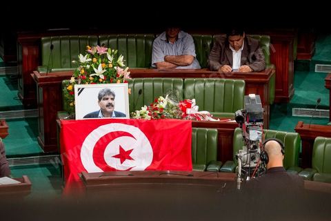 06 août 2013 : en place du siège du député assassiné  Mohamed Brahmi, des gerbes, son portrait et un drapeau national à la première séance de l'Assemblée depuis l'assassinat du député Mohamed Brahmi. La séance plénière débute par un long hommage au martyr avec prières et discours en présence des députés, hormis les 57 en retrait, du Premier Ministre et des ministres de l'Intérieur et de la Défense qui par leurs discours exposeront la situation dans le pays.