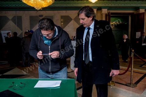 Devant l'entrée de l'hémicycle de l'Assemblée le député de l'opposition Selim Abdelsalem remet à Tammem les amendements au projet de loi sur la justice transitionnelle que Tammem photographie pour les publier sur leur site.