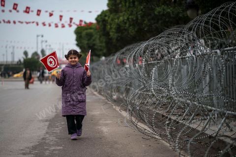 Une petite fille lors de la célébration du 3ème anniversaire de la Révolution à Tunis devant la barbelés en face du Ministère de l'Intérieur.