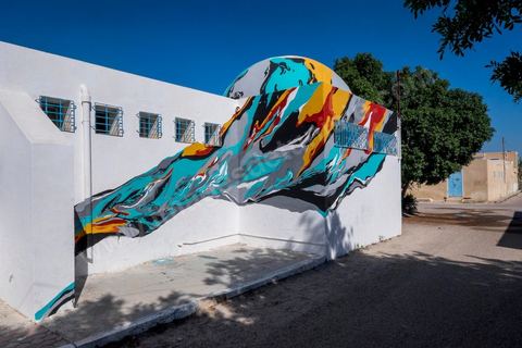 Oeuvre de l'artiste portugais ARRAIANO pour le Projet DjerbaHood : après la Tour Paris 13, la team Itinerrance dépose ses valises dans un village traditionnel de l’île de Djerba, Erriadh. Depuis le début du mois de juillet, le village d’Erriadh se métamorphose petit à petit pour devenir un véritable musée à ciel ouvert. Une sélection d’artistes des quatre coins du monde ont été invités à s’exprimer dans ce décor unique à l’architecture authentique : murs blancs, portes bleues turquoises, dômes, veilles constructions et divers lieux abandonnés, autant de possibilités qui donneront naissance à des créations uniques aux couleurs locales.