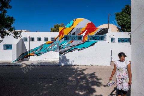 Oeuvre de l'artiste portugais ARRAIANO pour le Projet DjerbaHood : après la Tour Paris 13, la team Itinerrance dépose ses valises dans un village traditionnel de l’île de Djerba, Erriadh. Depuis le début du mois de juillet, le village d’Erriadh se métamorphose petit à petit pour devenir un véritable musée à ciel ouvert. Une sélection d’artistes des quatre coins du monde ont été invités à s’exprimer dans ce décor unique à l’architecture authentique : murs blancs, portes bleues turquoises, dômes, veilles constructions et divers lieux abandonnés, autant de possibilités qui donneront naissance à des créations uniques aux couleurs locales.