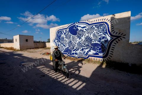 Oeuvre de l'artiste mexicain CURIOT pour le Projet DjerbaHood : après la Tour Paris 13, la team Itinerrance dépose ses valises dans un village traditionnel de l’île de Djerba, Erriadh. Depuis le début du mois de juillet, le village d’Erriadh se métamorphose petit à petit pour devenir un véritable musée à ciel ouvert. Une sélection d’artistes des quatre coins du monde ont été invités à s’exprimer dans ce décor unique à l’architecture authentique : murs blancs, portes bleues turquoises, dômes, veilles constructions et divers lieux abandonnés, autant de possibilités qui donneront naissance à des créations uniques aux couleurs locales.