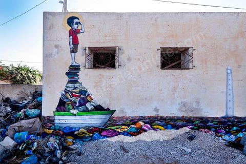 Oeuvre de l'artiste brésilien TINHO pour le Projet DjerbaHood : après la Tour Paris 13, la team Itinerrance dépose ses valises dans un village traditionnel de l’île de Djerba, Erriadh. Depuis le début du mois de juillet, le village d’Erriadh se métamorphose petit à petit pour devenir un véritable musée à ciel ouvert. Une sélection d’artistes des quatre coins du monde ont été invités à s’exprimer dans ce décor unique à l’architecture authentique : murs blancs, portes bleues turquoises, dômes, veilles constructions et divers lieux abandonnés, autant de possibilités qui donneront naissance à des créations uniques aux couleurs locales.