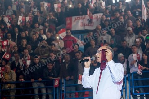 14 décembre 2014 : Au milieu de son speech, deux jeunes femmes sont arrivées sur le podium en ramenant un cadeau au candidat au second tour de l’élection présidentielle une cravate rouge ! Connu pour avoir toujours refusé de porter de cravate, afin de ne pas rompre son élan populiste, Moncef Marzouki a accepté le cadeau des deux jeunes filles et l’a même porté sur le champ. Grand meeting de Moncef Marzouki qui fait salle comble à la coupole de Tunis à une semaine du 2d tour des élections présidentielles. Moncef Marzouki, a appelé ses partisans, « à ne pas tomber dans le piège des insultes et à ne pas dire du mal de son rival Béji Caid Essebsi », tout en affirmant «nous avons le droit de juger cet homme pour son passé et pour son rôle destructeur au cours de la phase transitoire…, mais notre combat est celui des valeurs et l’éthique».Le président sortant et candidat au second tour de la présidentielle a tenu dimanche un meeting au palais des sports d’El Menzah. Ses partisans venus des différentes régions du pays ont scandé des slogans hostiles à son rival Béji Caid Essebsi et à son parti Nidaa Tounes.