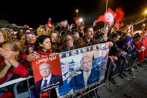 21 décembre 2014 : Militant avec portrait historique de Habib Bourguiba et de Béji Caid Essebsi. Dès la fin du scrutin à 18h, les rumeurs d'une large victoire de Beji Caïd Essebsi, candidat du parti Nidaa Tounes, circulent. Avec 8 à 10 points d'avance selon les sondages, Béji Caid Essebsi remporte les 1ères élections présidentielles libres en Tunisie depuis la révolution de 2011. A cette annonce les militants sont venus nombreux féter la victoire annoncée devant le QG de campagne du parti dans le quartier très huppé des Berges du Lac de Tunis.