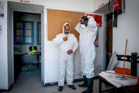 11 juin 2017 : Chemseddine Marzoug et Mohamed Trabelsi dans le local du croissant rouge tunisien de Zarzis s'équipent de leur tenue pour récupérer les corps de migrants. A Zarzis, sur le littoral tunisien, frontalier de la Libye, Chemseddine Marzoug, ancien pêcheur au chomage, offre bénévolement depuis 10 ans une sépulture de sable aux noyés de la Méditerranée. Bénévoles pour le croissant rouge tunisien Chemseddine et son collègue Mohamed Trabelsi enterrent depuis 10 ans les corps des migrants trouvés en mer ou échoués sur les plages du sud tunisien dans un cimetière improvisé dans une décharge municipale. En cette saison de printemps, les morts sont très nombreux 27 corps ont été repêchés ce dernier mois. 