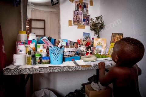 24 juin 2017 : Dans la chambre, la seule table est occupée par les produits de beauté et un autel dédié à Dieu. Chez Océane, migrante Ivoirienne à Tunis dans un quartier populaire. Elle vit dans une maison avec 2 chambres qu'elle partage avec son fils Eden et cinq autres ivoiriennes. Océane est arrivée en Tunisie en 2010 comme étudiante et est depuis 5 ans en situation irrégulière, ne lui permettant plus de travailler légalement. Il y a deux ans Eden est né, ce jeune garçon plein de joie est devenu sa raison de vivre, elle souhaite trouver un endroit pour vivre normalement et élever son fils. “J’estime que pour vivre bien Tunisie, il me faudrait entre 800 et 1000 dinars. Généralement, je suis plutôt à 350. Entre les couches et la nourriture, les dépenses sont rapides.” La jeune femme travaille de façon irrégulière : elle a quelques patrons qui l’appellent, selon leur besoin, pour faire le ménage chez eux. Une journée lui rapporte entre 25 et 30 dinars.  