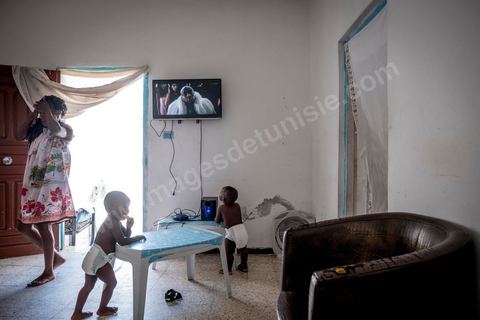 24 juin 2017 : Chez Océane, migrante Ivoirienne à Tunis dans un quartier populaire. Elle vit dans une maison avec 2 chambres qu'elle partage avec son fils Eden et cinq autres ivoiriennes. Océane est arrivée en Tunisie en 2010 comme étudiante et est depuis 5 ans en situation irrégulière, ne lui permettant plus de travailler légalement. Il y a deux ans Eden est né, ce jeune garçon plein de joie est devenu sa raison de vivre, elle souhaite trouver un endroit pour vivre normalement et élever son fils. “J’estime que pour vivre bien Tunisie, il me faudrait entre 800 et 1000 dinars. Généralement, je suis plutôt à 350. Entre les couches et la nourriture, les dépenses sont rapides.” La jeune femme travaille de façon irrégulière : elle a quelques patrons qui l’appellent, selon leur besoin, pour faire le ménage chez eux. Une journée lui rapporte entre 25 et 30 dinars.  