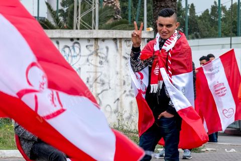 18 février 2018 : Au parc A du CA, les supporters se retrouvent et font leurs derniers achats de banderolles et écharpes avantd e rejoindre le stade pour le match. A Tunis c'est le grand jour celui du Derby Foot, le match entre les deux meilleures équipes actuelles du championnat et les deux équipes phares de Tunis, le Club Africain (CA) contre l'Espérance de Tunis (EST) au grand stade de Radès dans la banlieue sud de Tunis. Ce match retour est à l'avantage du CA qui dispose de la billetterie. Au vu des nombreux affrontements de supporters et des groupes d'ultras dans les stades entre eux et avec la police, seulement 23000 billets sont mis en vente (pour une capacité de 60000) dont 1200 pour l'EST mais qui ne seront qu'une petite cinquantaine dans la tribune sud. Le match se terminera par la victoire surprise du CA sur le score de 2 à 1. 
