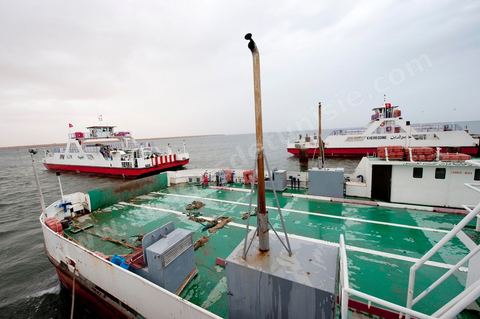 Adjim, sur la côte sud-ouest de Djerba, est le point de départ du bac qui relie l'île au continent, à Jorf, à travers le chenal séparant Djerba de la Tunisie continentale. Le port, encore marqué par une activité de pêche traditionnelle, offre des ambiances changeantes au fil de la journée, entre lever et coucher de soleil sur la mer, bateaux amarrés et silhouettes des jetées.