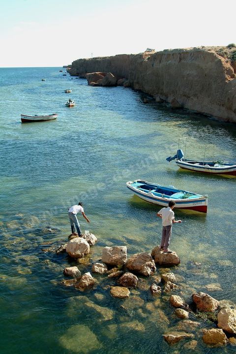 Adjim, sur la côte sud-ouest de Djerba, est le point de départ du bac qui relie l'île au continent, à Jorf, à travers le chenal séparant Djerba de la Tunisie continentale. Le port, encore marqué par une activité de pêche traditionnelle, offre des ambiances changeantes au fil de la journée, entre lever et coucher de soleil sur la mer, bateaux amarrés et silhouettes des jetées.