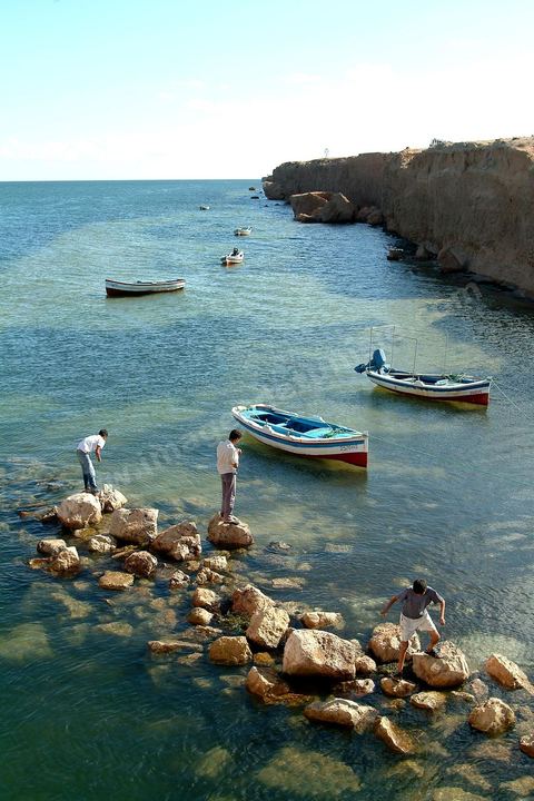 Adjim, sur la côte sud-ouest de Djerba, est le point de départ du bac qui relie l'île au continent, à Jorf, à travers le chenal séparant Djerba de la Tunisie continentale. Le port, encore marqué par une activité de pêche traditionnelle, offre des ambiances changeantes au fil de la journée, entre lever et coucher de soleil sur la mer, bateaux amarrés et silhouettes des jetées.