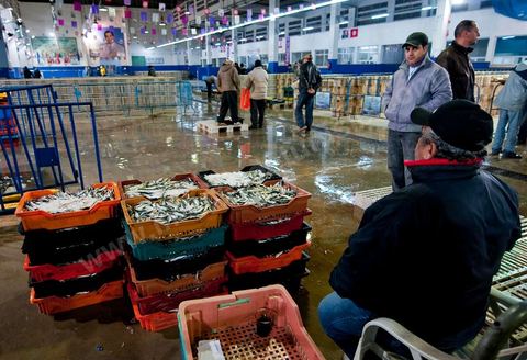 Vendeur avec caisses de poissons à la Halle aux poissons du marché de gros de Tunis à El Mourouj