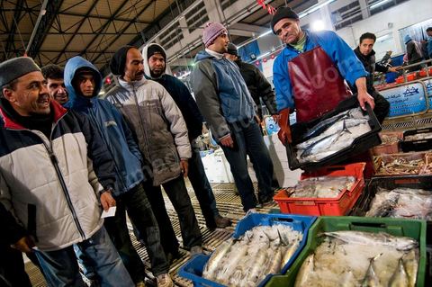 Vendeur avec caisses de poissons à la Halle aux poissons du marché de gros de Tunis à El Mourouj