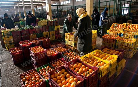 Vendeur et étales de oranges et pommes à la Halle aux fruits et légumes du marché de gros de Tunis à El Mourouj