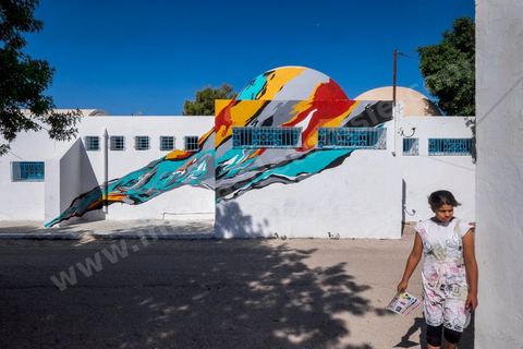 Oeuvre de l'artiste portugais ARRAIANO pour le Projet DjerbaHood : après la Tour Paris 13, la team Itinerrance dépose ses valises dans un village traditionnel de l’île de Djerba, Erriadh. Depuis le début du mois de juillet, le village d’Erriadh se métamorphose petit à petit pour devenir un véritable musée à ciel ouvert. Une sélection d’artistes des quatre coins du monde ont été invités à s’exprimer dans ce décor unique à l’architecture authentique : murs blancs, portes bleues turquoises, dômes, veilles constructions et divers lieux abandonnés, autant de possibilités qui donneront naissance à des créations uniques aux couleurs locales.