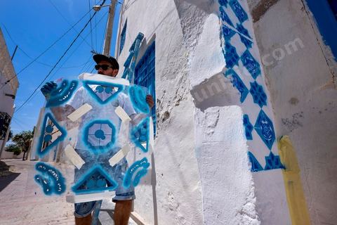 Oeuvre de l'artiste portugais ADD FUEL pour le Projet DjerbaHood : après la Tour Paris 13, la team Itinerrance dépose ses valises dans un village traditionnel de l’île de Djerba, Erriadh. Depuis le début du mois de juillet, le village d’Erriadh se métamorphose petit à petit pour devenir un véritable musée à ciel ouvert. Une sélection d’artistes des quatre coins du monde ont été invités à s’exprimer dans ce décor unique à l’architecture authentique : murs blancs, portes bleues turquoises, dômes, veilles constructions et divers lieux abandonnés, autant de possibilités qui donneront naissance à des créations uniques aux couleurs locales.