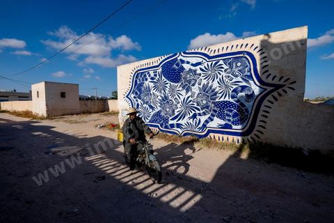Oeuvre de l'artiste mexicain CURIOT pour le Projet DjerbaHood : après la Tour Paris 13, la team Itinerrance dépose ses valises dans un village traditionnel de l’île de Djerba, Erriadh. Depuis le début du mois de juillet, le village d’Erriadh se métamorphose petit à petit pour devenir un véritable musée à ciel ouvert. Une sélection d’artistes des quatre coins du monde ont été invités à s’exprimer dans ce décor unique à l’architecture authentique : murs blancs, portes bleues turquoises, dômes, veilles constructions et divers lieux abandonnés, autant de possibilités qui donneront naissance à des créations uniques aux couleurs locales.