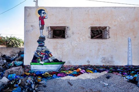 Oeuvre de l'artiste brésilien TINHO pour le Projet DjerbaHood : après la Tour Paris 13, la team Itinerrance dépose ses valises dans un village traditionnel de l’île de Djerba, Erriadh. Depuis le début du mois de juillet, le village d’Erriadh se métamorphose petit à petit pour devenir un véritable musée à ciel ouvert. Une sélection d’artistes des quatre coins du monde ont été invités à s’exprimer dans ce décor unique à l’architecture authentique : murs blancs, portes bleues turquoises, dômes, veilles constructions et divers lieux abandonnés, autant de possibilités qui donneront naissance à des créations uniques aux couleurs locales.