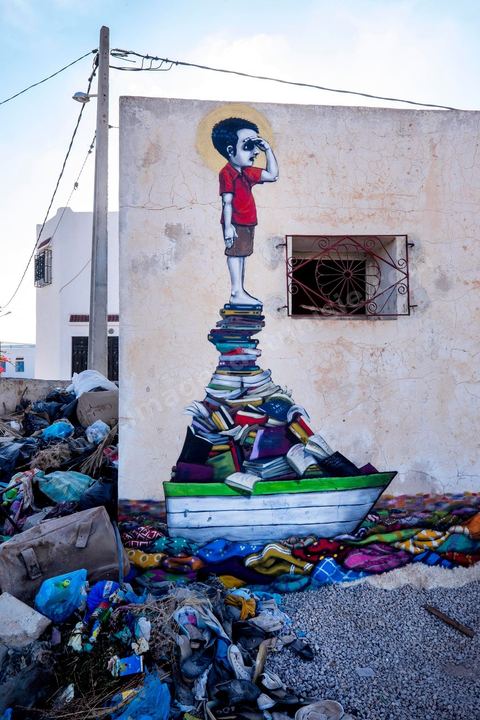 Oeuvre de l'artiste brésilien TINHO pour le Projet DjerbaHood : après la Tour Paris 13, la team Itinerrance dépose ses valises dans un village traditionnel de l’île de Djerba, Erriadh. Depuis le début du mois de juillet, le village d’Erriadh se métamorphose petit à petit pour devenir un véritable musée à ciel ouvert. Une sélection d’artistes des quatre coins du monde ont été invités à s’exprimer dans ce décor unique à l’architecture authentique : murs blancs, portes bleues turquoises, dômes, veilles constructions et divers lieux abandonnés, autant de possibilités qui donneront naissance à des créations uniques aux couleurs locales.