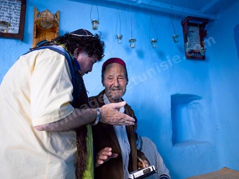 Pelerins juifs déposant des cierges et priant dans une petite synagogue bleue à Hara Sghira Erriadh durant le pelerinage juif annuel au village de Erriadh ou Hara Sghira sur l'ile de djerba