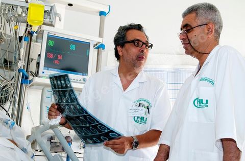 Le Dr Tahar Khalfallah (premier plan), chirurgien, et le Dr Mohamed Salah Ben Ammar (au second plan), anesthésiste, durant une consultation auprès d'un patient au service réanimation à l'hopital Mongi Slim de la Marsa