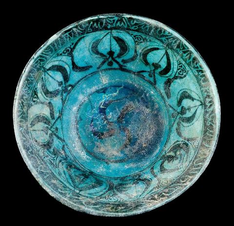 COUPE AUX FLEURONS.Syrie, attribuée à Raqqa, 13  siècle.Céramique silicieuse, large frise de huit fleurons bordée d'une frise haute imitant une écriture.