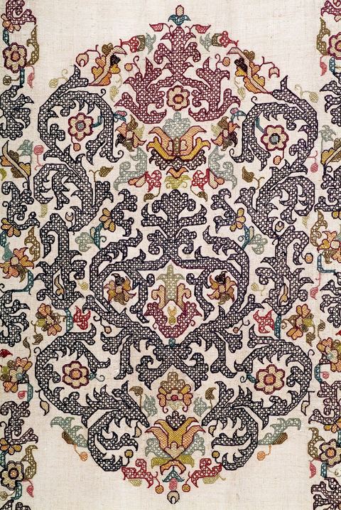 TENTURE À DÉCOR DE RINCEAUX FLEURIS. Alger, 18  siècle.Lin brodé de fil de soie polychrome à dominante violette. Aux extrémités, une rivière travaillée à  l'aiguille et exécutée en soie grège. En vogue à Alger, la teinte violette, issue du bois de campêche (importé d'Amérique), était très rare dans la broderie méditerranéenne. Chef-d'oeuvre de la broderie algérienne, cet ouvrage emprunte, en partie, son répertoire floral à l'herbier de la Turquie ottomane et sa composition, en gros rinceaux fleuris, à la Renaissance italienne. Une trace lointaine des puissantes compositions de l'art maghrébin almohade (12 - 13  siècle) n'est pas exclue.Recherchée en Europe, l'exemplaire le plus ancien de la broderie d'Alger se trouve en France. Il pare aujourd'hui 'La vierge noire' de Notre-Dame-du-Pilier à la Cathédrale de Chartres.