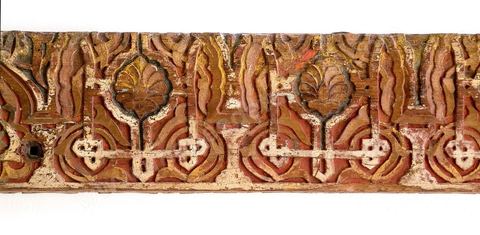 FRISE AU 'YOMN'.Maroc alaouide,18  siècle.Deux décors ornent cette frise. Sur un fond de rinceaux fleuris de demi-palmettes, un arc polylobé (incomplet) haut est meublée d'une coquille. De part et d'autre, s'inscrit, en miroir, le mot 'Yomn', la 'faveur divine'. Un arc plus bas (complet), en ogive, est orné d'unfleuron central et de demi-palmettes.Ce bois, ouvragé, tardif, témoigne de la survivance d'un beau répertoire classique, andalou-maghrébin, au Maroc alaouide (1640-     ).Salle des Arts du Maghreb - Musée Lalla Hadria - Parc Djerba Explore