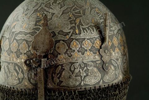 CASQUE DE CÉRÉMONIE.Perse qâdjâre,19  siècle.Acier, Or et Argent.Cette forme, en pointe, est archaïsante et se retrouve dans de nombreuses miniatures à thème guerrier. Le repertoire iconographique, scène de chasse à courre, où abondent les figures humaines et animalières, permet de situer le casque dans la série des armures à usage cérémonial, caractéristique des rites chîîtes. Apporté, vraisemblablement, par les turcs, ce genre de casque se retrouvait en Tunisie. Un casque dit, 'de Rostam' est conservé au Musée Militaire du Palais de la Rose, dans la banlieue de Tunis.	 - Musée Lella Hadria à Djerba Explore
