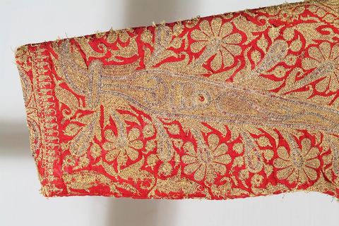 CAFETAN AUX CYPRÈSPerse/Asie Centrale, 19  siècle.Composition très dense caractéristique des costumes d'Asie Centrale. Décors de cyprès et de rinceaux fleuris en fil d'or et d'argent sur fond de soie rouge.Un type de cafetan comparable aurait été porté à Alger durant la période ottomane.