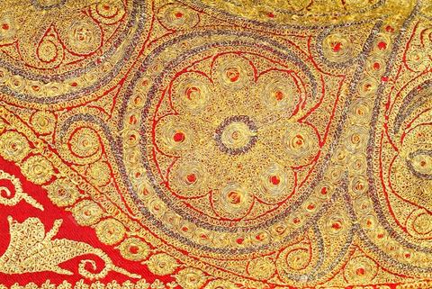 CAFETAN AUX CYPRÈSPerse/Asie Centrale, 19  siècle.Composition très dense caractéristique des costumes d'Asie Centrale. Décors de cyprès et de rinceaux fleuris en fil d'or et d'argent sur fond de soie rouge.Un type de cafetan comparable aurait été porté à Alger durant la période ottomane.