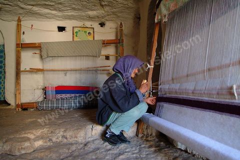 Femme tissant à l'intérieur d'une maison traditionnelle dans le village de Douiret