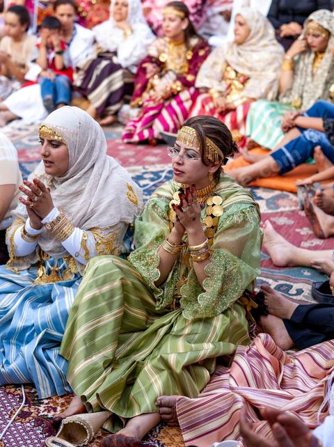Lors d'un mariage traditionnel à Djerba, la soirée des femmes rassemble la communauté autour de la mariée, parée de la haajba, la tenue nuptiale djerbienne aux ornements précieux transmise de génération en génération. La musique est portée par des chanteuses et musiciens noirs, descendants des communautés subsahariennes établies sur l'île, qui animent la fête au son de la darbouka et du tambour, dans une tradition musicale propre au mariage djerbien.