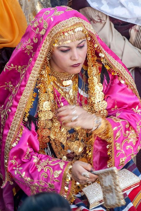 Lors d'un mariage traditionnel à Djerba, la soirée des femmes rassemble la communauté autour de la mariée, parée de la haajba, la tenue nuptiale djerbienne aux ornements précieux transmise de génération en génération. La musique est portée par des chanteuses et musiciens noirs, descendants des communautés subsahariennes établies sur l'île, qui animent la fête au son de la darbouka et du tambour, dans une tradition musicale propre au mariage djerbien.