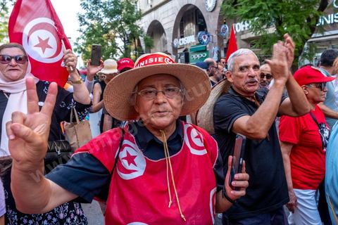 Tunis, Tunisia – August 20, 2026. Protesters march through downtown Tunis against President Kaïs Saïed, calling for his resignation and demanding greater political freedoms and the release of detainees and opposition figures. Portraits of the president crossed out with the slogan “GET OUT,” Tunisian flags, and signs accompany the protest. The protest comes amid growing social discontent following several weeks of extreme heat, water and power outages, and difficulties in accessing certain medications and essential goods.