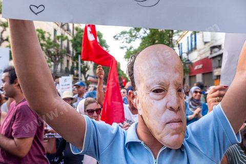 Tunis, Tunisia – August 20, 2026. Protesters march through downtown Tunis against President Kaïs Saïed, calling for his resignation and demanding greater political freedoms and the release of detainees and opposition figures. Portraits of the president crossed out with the slogan “GET OUT,” Tunisian flags, and signs accompany the protest. The protest comes amid growing social discontent following several weeks of extreme heat, water and power outages, and difficulties in accessing certain medications and essential goods.