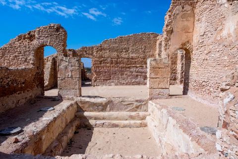 Thyna – l’antique Thaenae – est l’un des principaux sites archéologiques de la région de Sfax, situé à une douzaine de kilomètres au sud de la ville, sur le littoral tunisien. Ancienne cité punique, elle passe sous domination numide après la chute de Carthage en 146 av. J.-C., puis devient romaine en 46 av. J.-C. Élevée au rang de colonie au IIᵉ siècle, Thaenae connaît une importante prospérité durant l’époque romaine et reste occupée jusqu’à l’Antiquité tardive. Au IVᵉ siècle, la ville est protégée par une imposante enceinte de près de trois kilomètres, ponctuée de 84 tours et de trois portes. Aujourd’hui, le site conserve notamment les vestiges de ses remparts, de plusieurs établissements thermaux, dont les Thermes des Mois, de maisons antiques comme la Maison de Dionysos, ainsi que de vastes ensembles funéraires et nécropoles. Encore largement inexplorée, Thaenae fait aujourd’hui l’objet de nouvelles campagnes de recherches archéologiques et de valorisation.