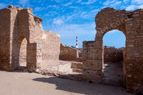 Thyna – l’antique Thaenae – est l’un des principaux sites archéologiques de la région de Sfax, situé à une douzaine de kilomètres au sud de la ville, sur le littoral tunisien. Ancienne cité punique, elle passe sous domination numide après la chute de Carthage en 146 av. J.-C., puis devient romaine en 46 av. J.-C. Élevée au rang de colonie au IIᵉ siècle, Thaenae connaît une importante prospérité durant l’époque romaine et reste occupée jusqu’à l’Antiquité tardive. Au IVᵉ siècle, la ville est protégée par une imposante enceinte de près de trois kilomètres, ponctuée de 84 tours et de trois portes. Aujourd’hui, le site conserve notamment les vestiges de ses remparts, de plusieurs établissements thermaux, dont les Thermes des Mois, de maisons antiques comme la Maison de Dionysos, ainsi que de vastes ensembles funéraires et nécropoles. Encore largement inexplorée, Thaenae fait aujourd’hui l’objet de nouvelles campagnes de recherches archéologiques et de valorisation.
